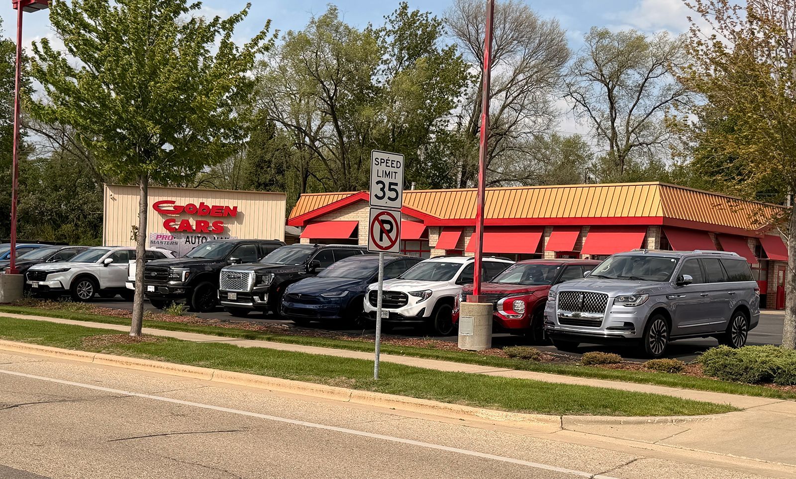 Parking lot outside a red-roofed fast-food restaurant with several cars parked in front.