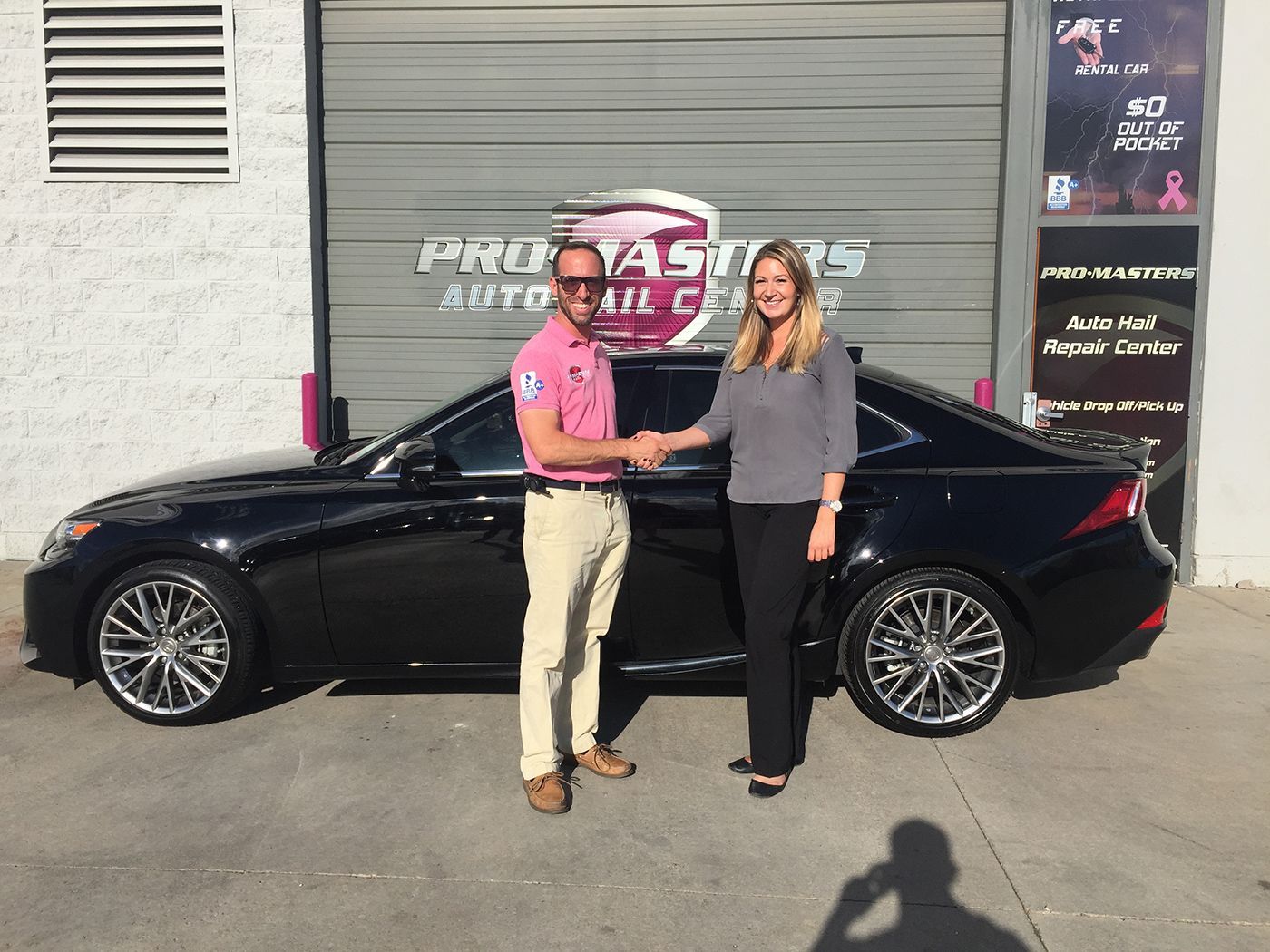 A man and woman shaking hands in front of a black car