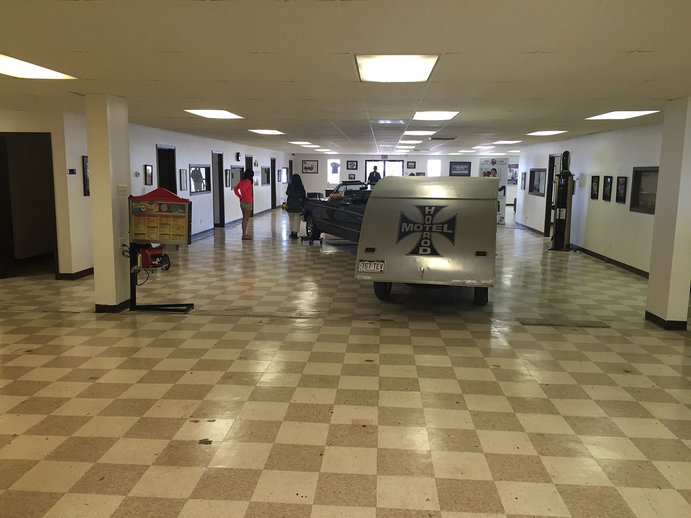 A large room with a checkered floor and a car in it