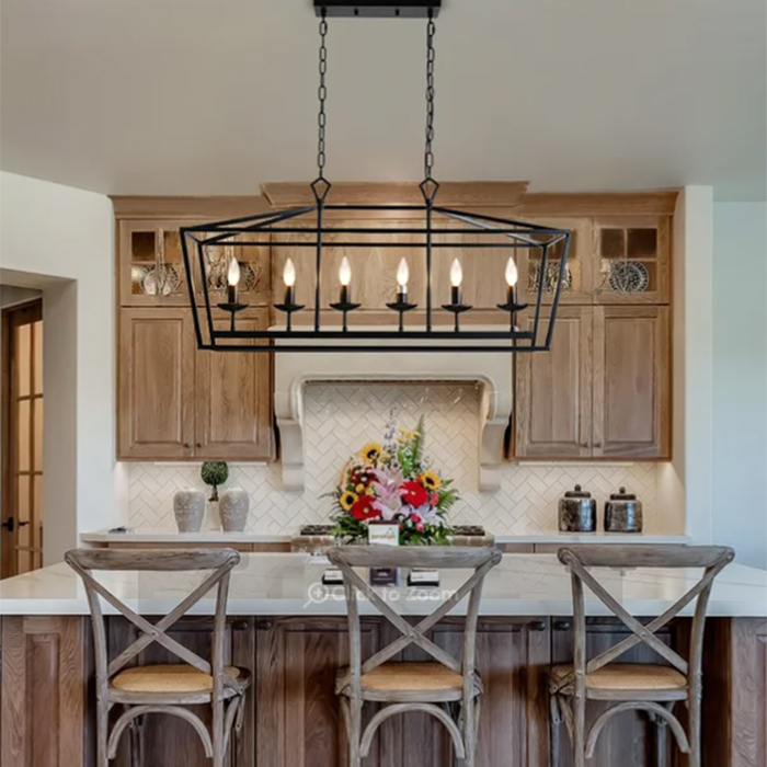 Kitchen with a large black chandelier above an island with three wooden chairs.