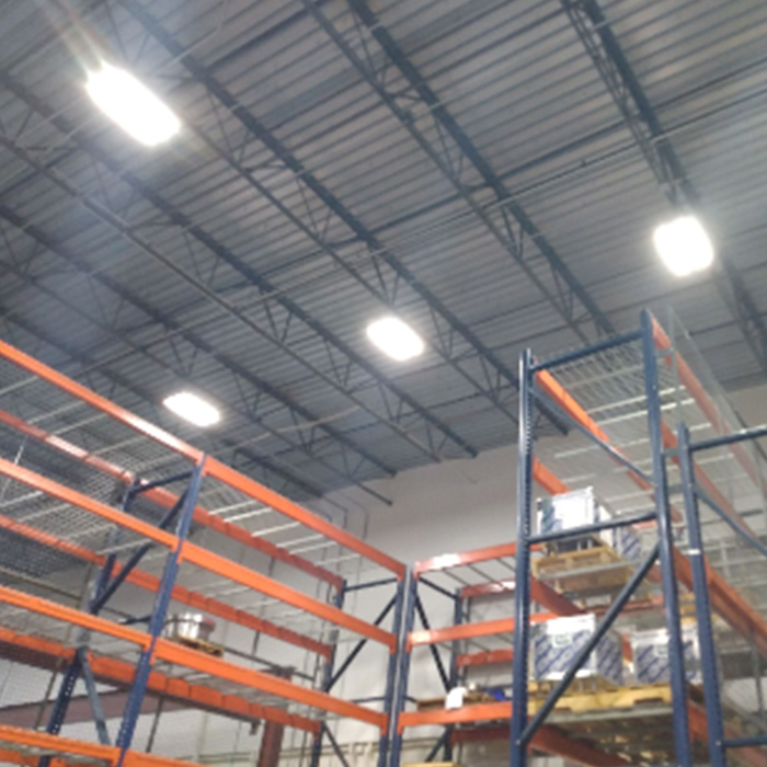 Warehouse interior with tall metal shelving, ceiling lights, and a corrugated metal roof.