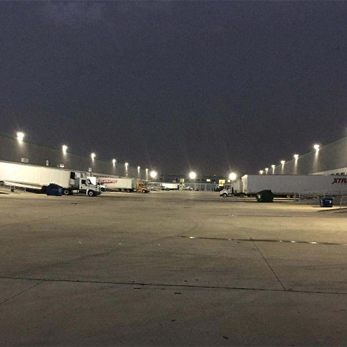 Trucks parked at a loading dock at night under bright lights.