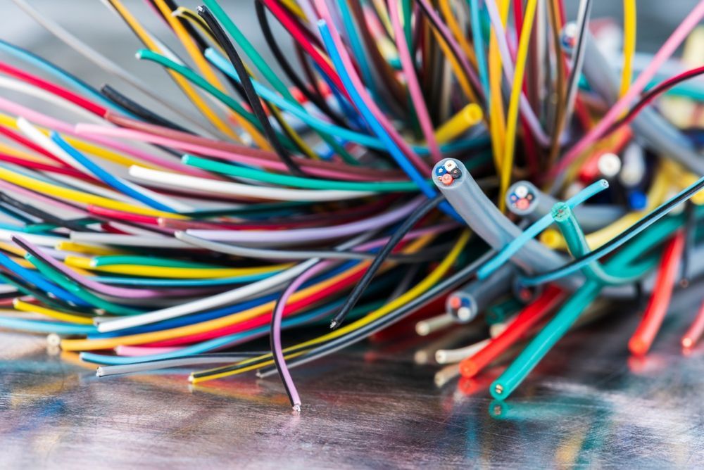 Colorful electrical wires in a tangled bundle on a reflective surface.