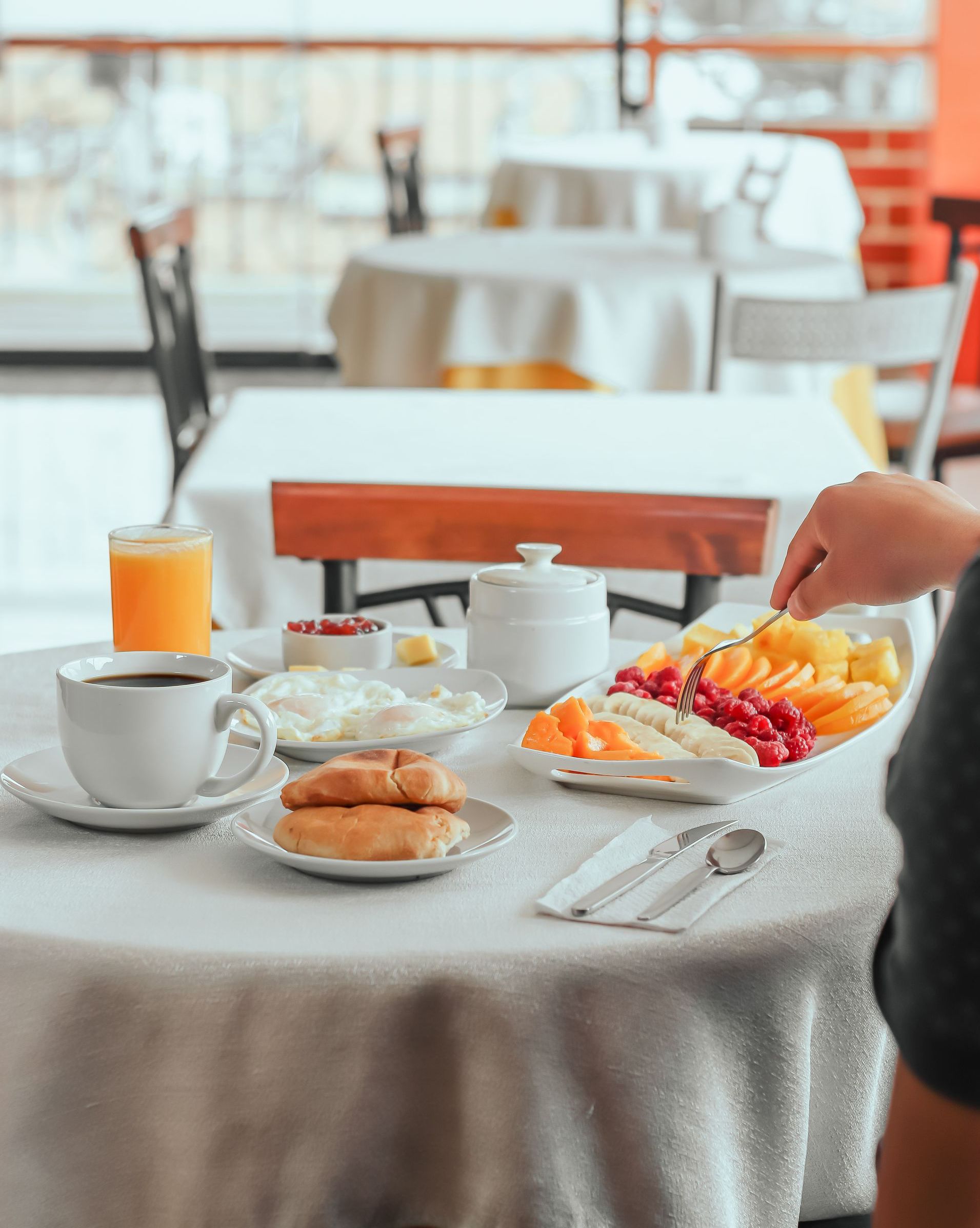 Una persona está sentada en una mesa con platos de comida y una taza de café.