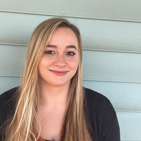 A woman with long blonde hair is smiling for the camera