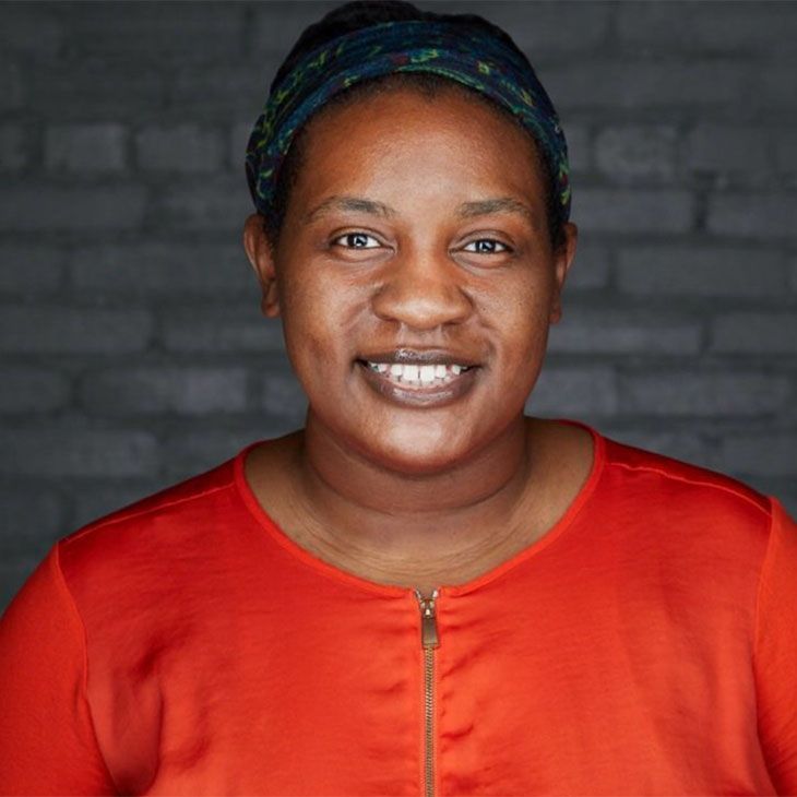 A woman wearing a red shirt and a headband is smiling for the camera.