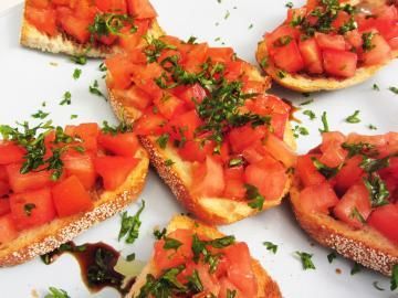 Bruschetta slices topped with diced tomatoes and herbs on a white plate