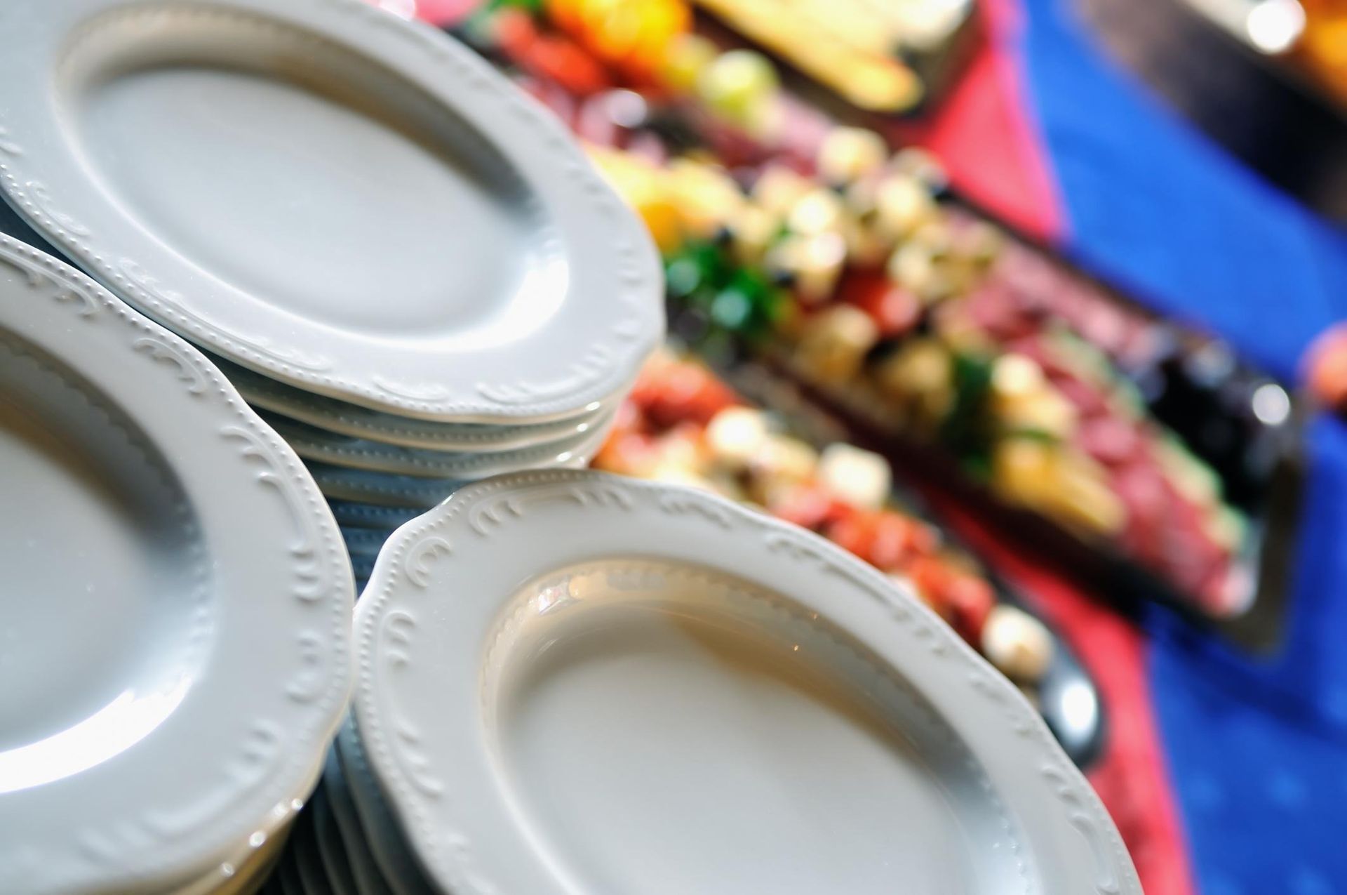 Stacks of white disposable plates beside colorful wrapped snacks on a table