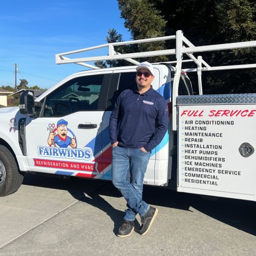 A man is standing in front of a fairwinds truck.