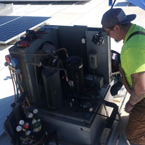 A man in a neon green shirt is working on a machine