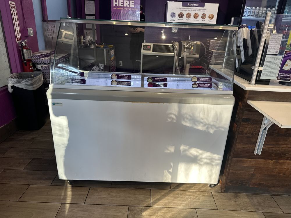 A large ice cream freezer is sitting in a restaurant.