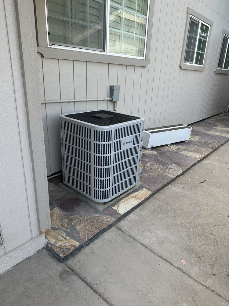 An air conditioner is sitting on the side of a building next to a window.