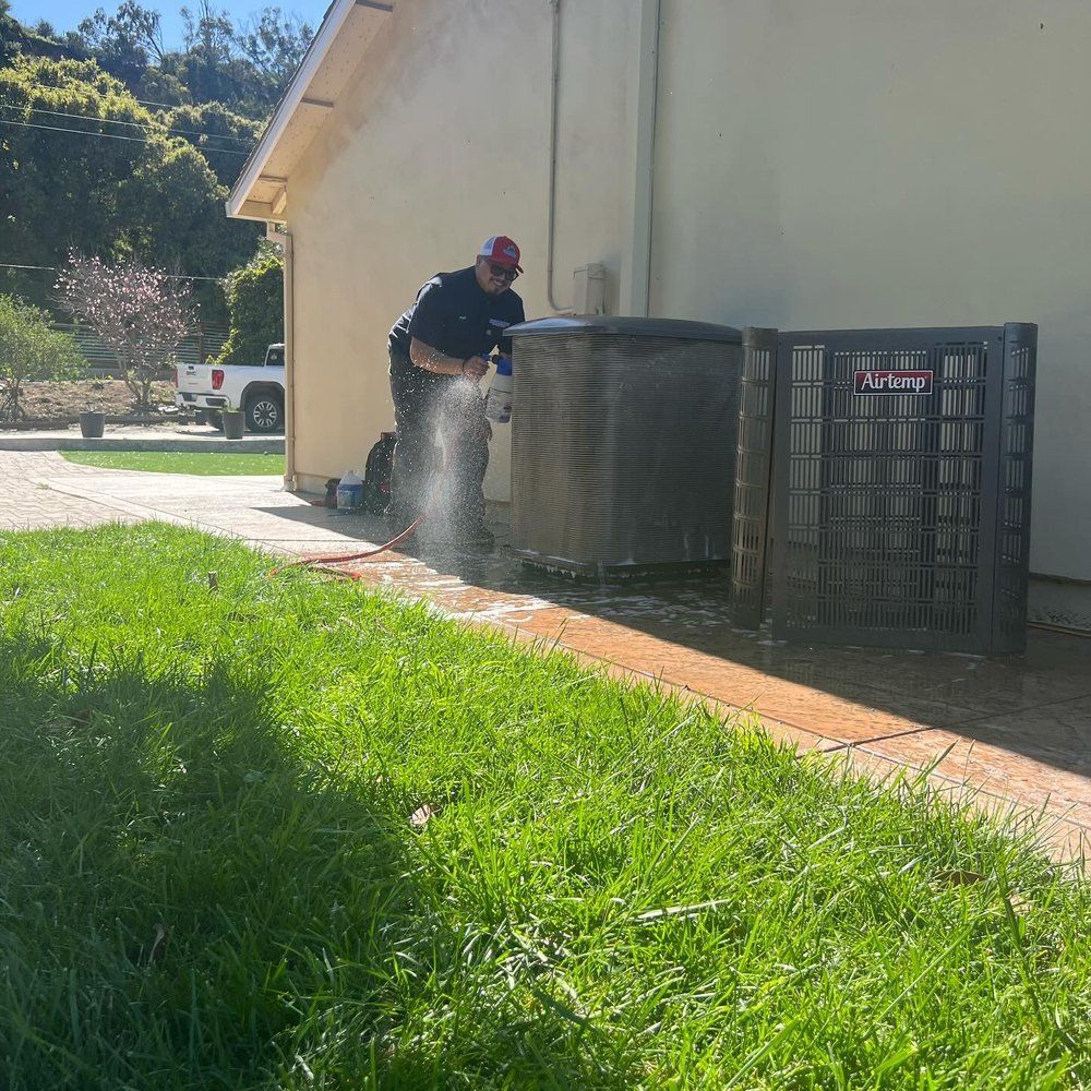 A man is working on an air conditioner outside of a house.