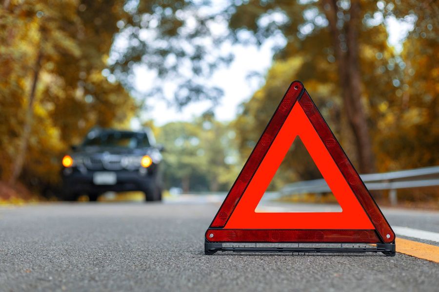A red triangle is sitting on the side of the road next to a car.