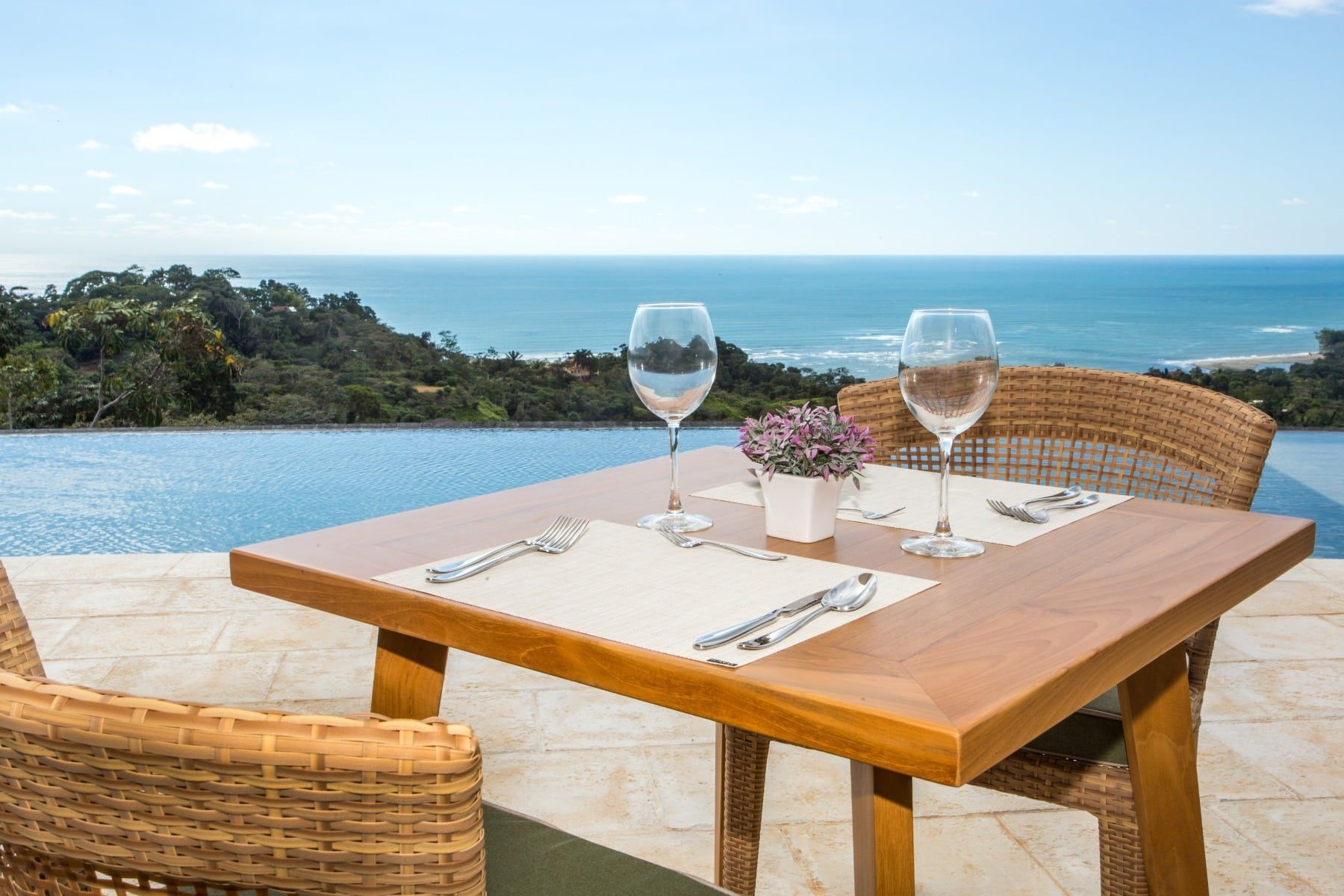 A table with two wine glasses on it and a view of the ocean.