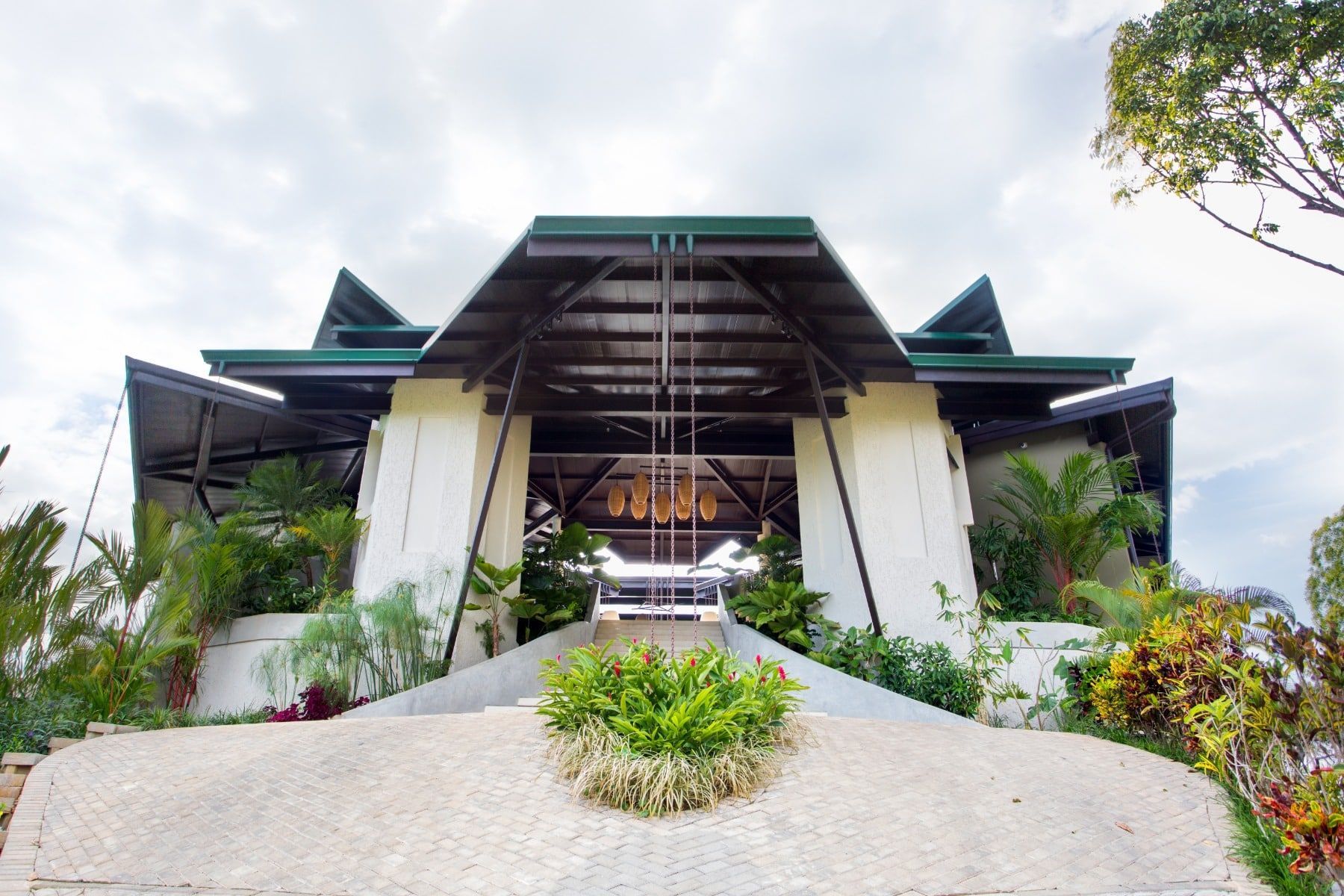 A large white building with a green roof is surrounded by trees and bushes.