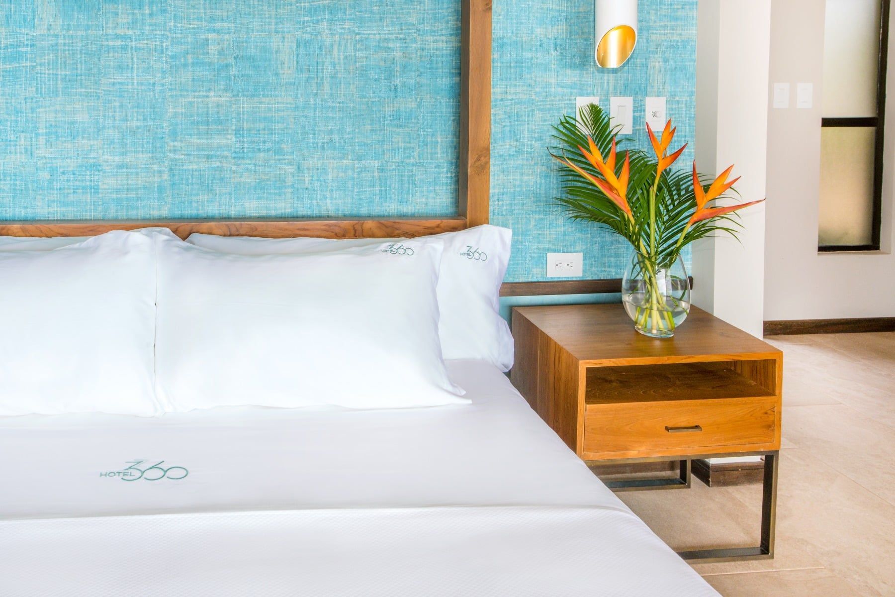 There is a vase of flowers on the nightstand next to the bed.