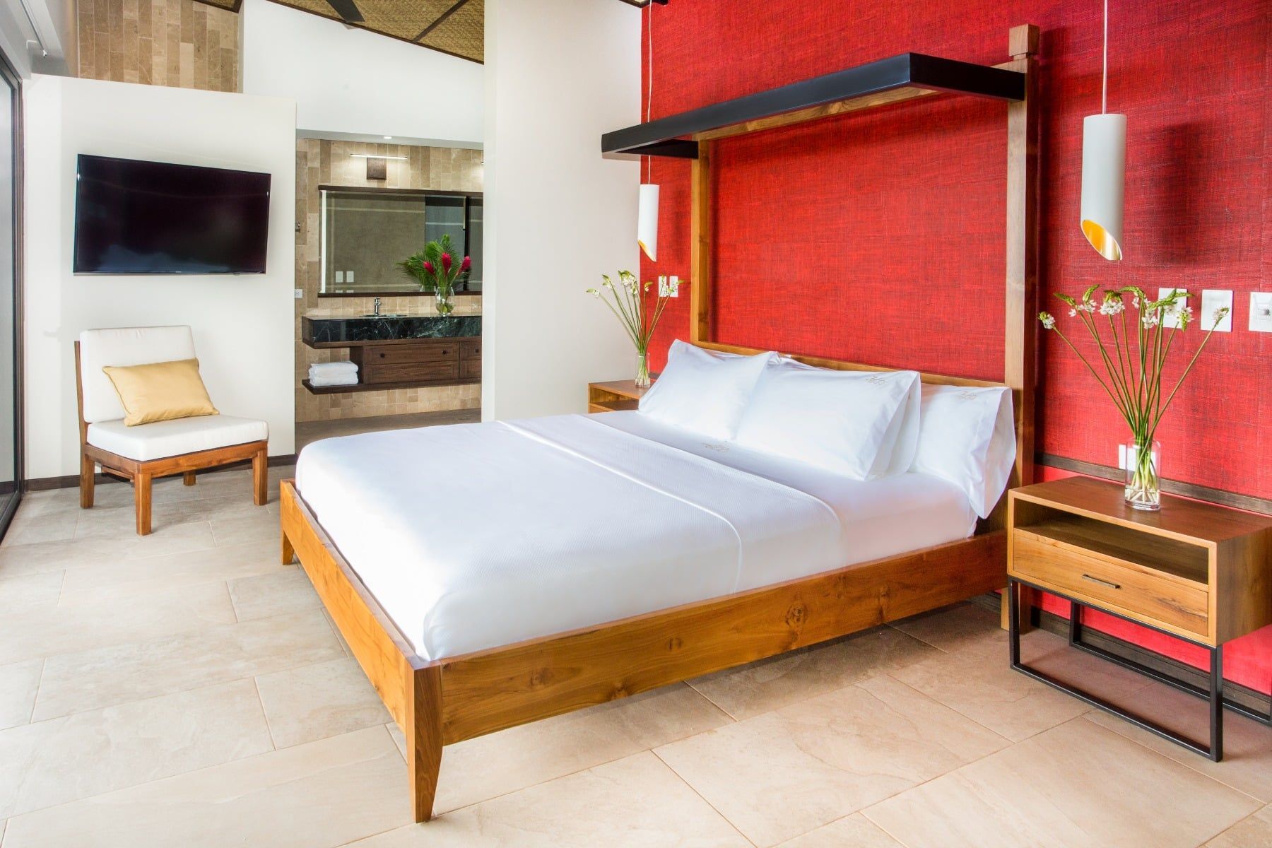 A bedroom with a large bed and a television on the wall.