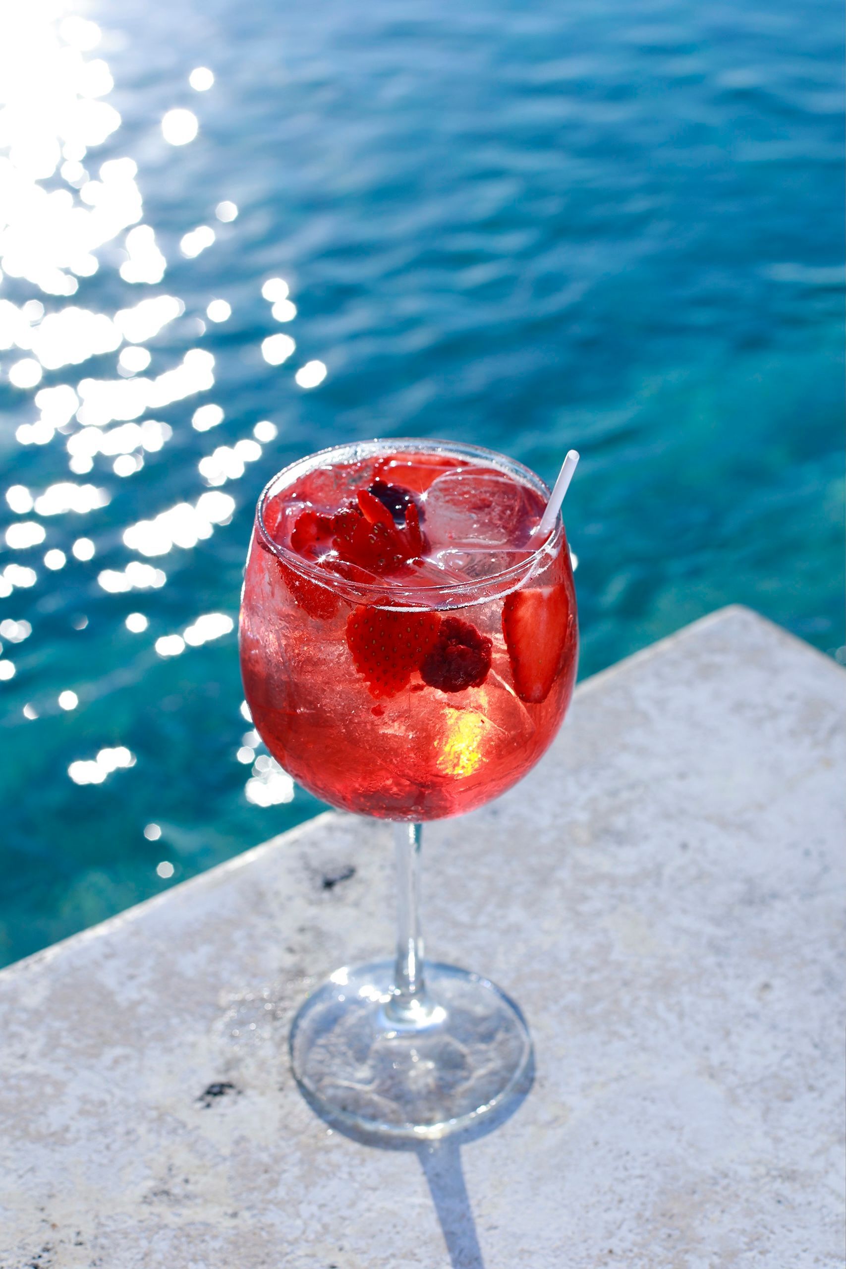 A glass of red liquid with strawberries in it