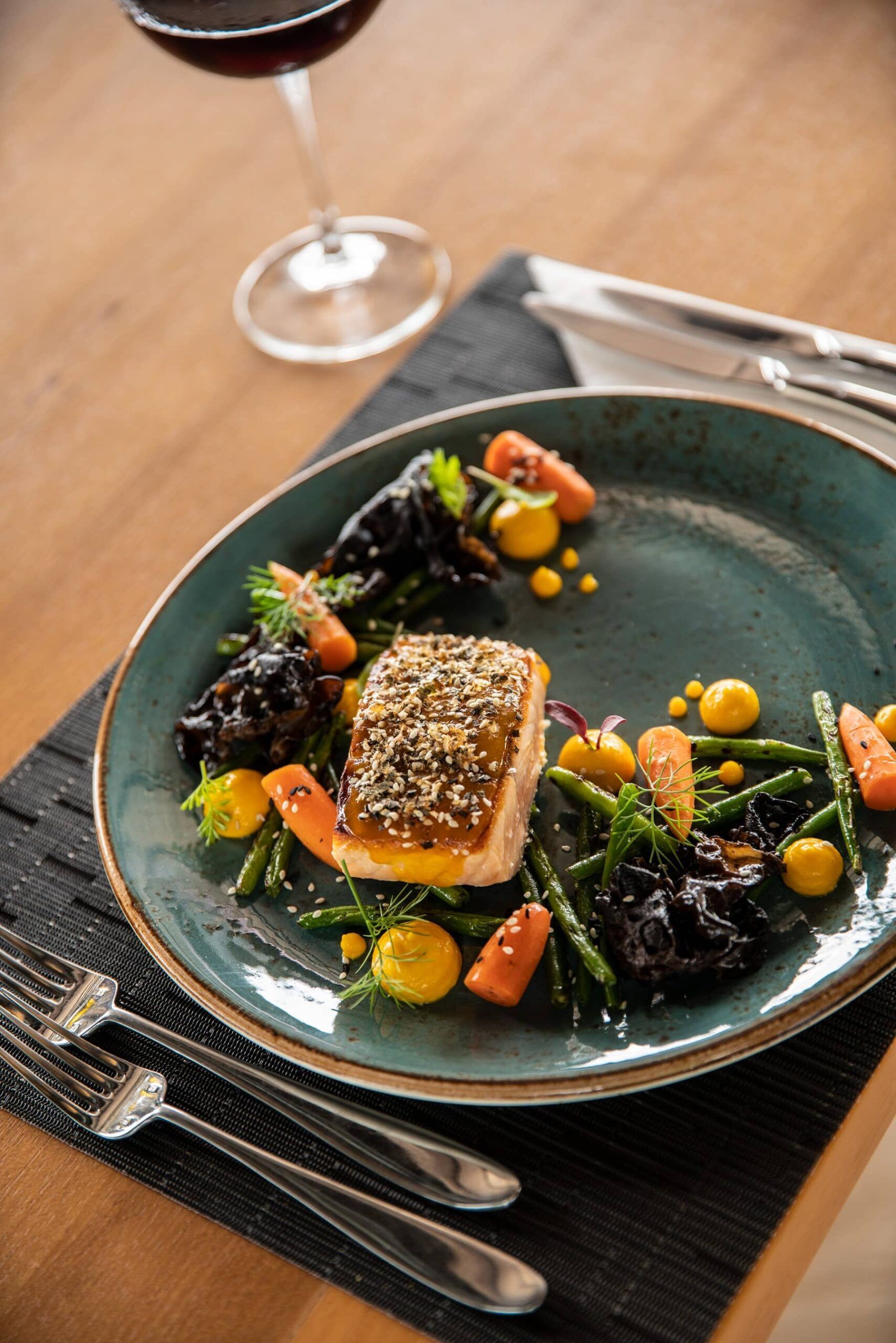 A plate of food with vegetables and a glass of wine on a table.