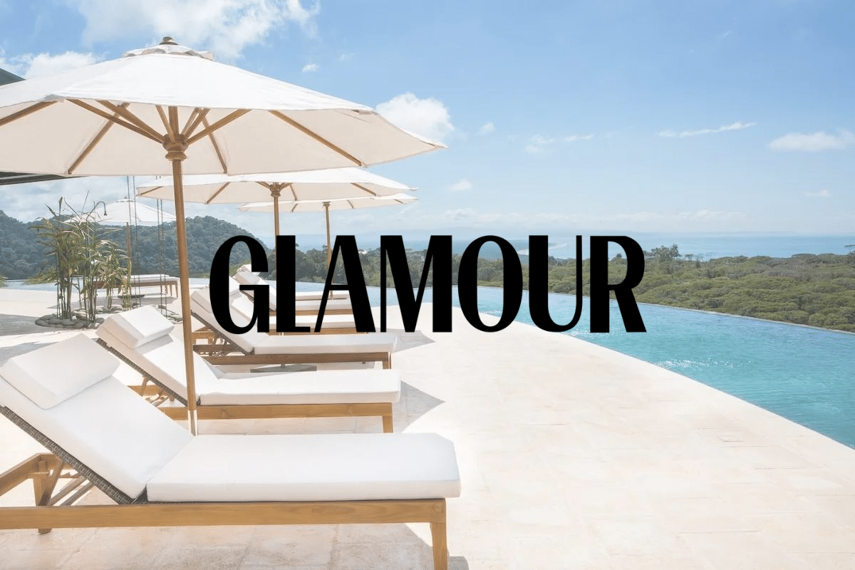 A row of lounge chairs under umbrellas next to a swimming pool.
