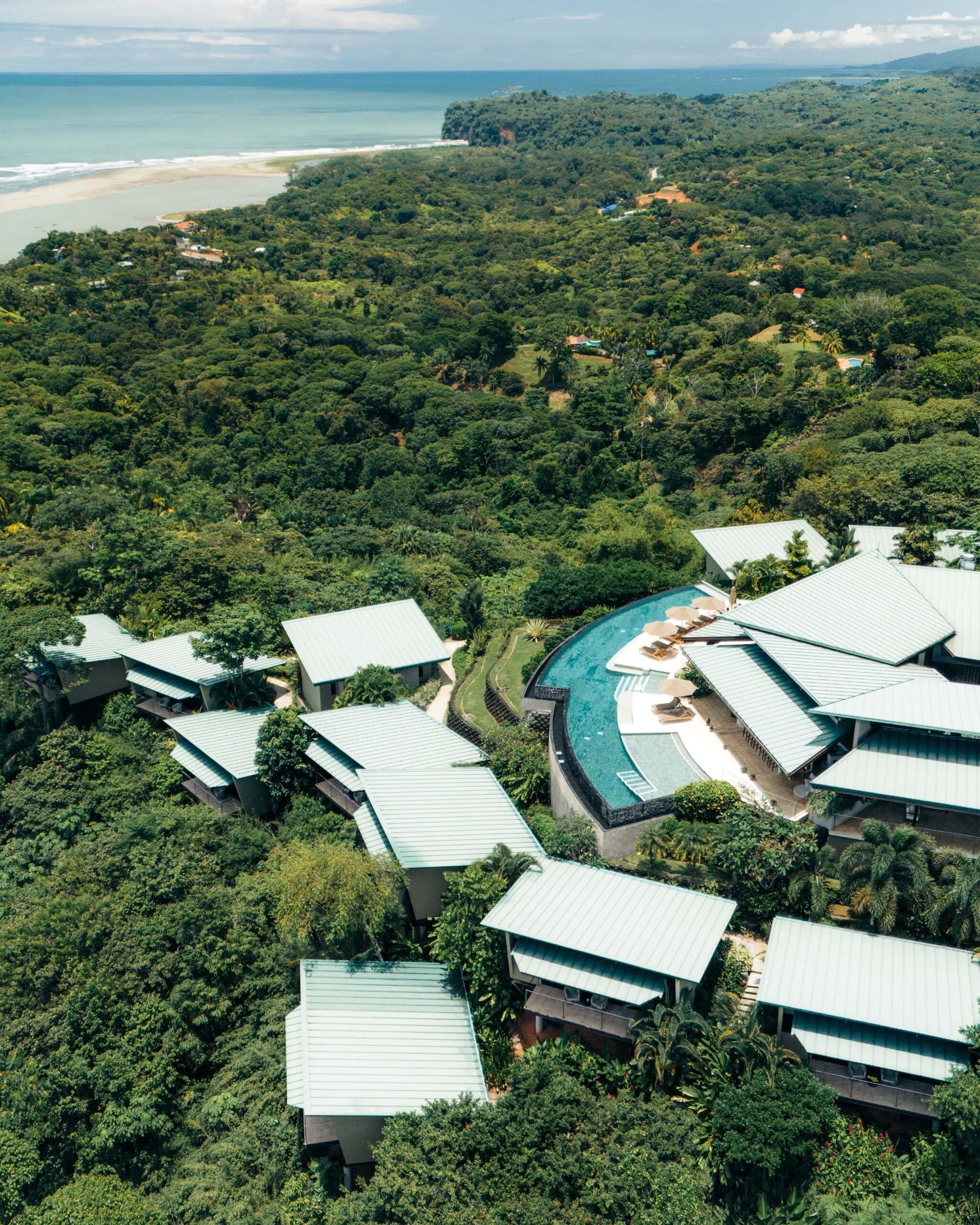 An aerial view of a resort in the middle of a lush green forest.