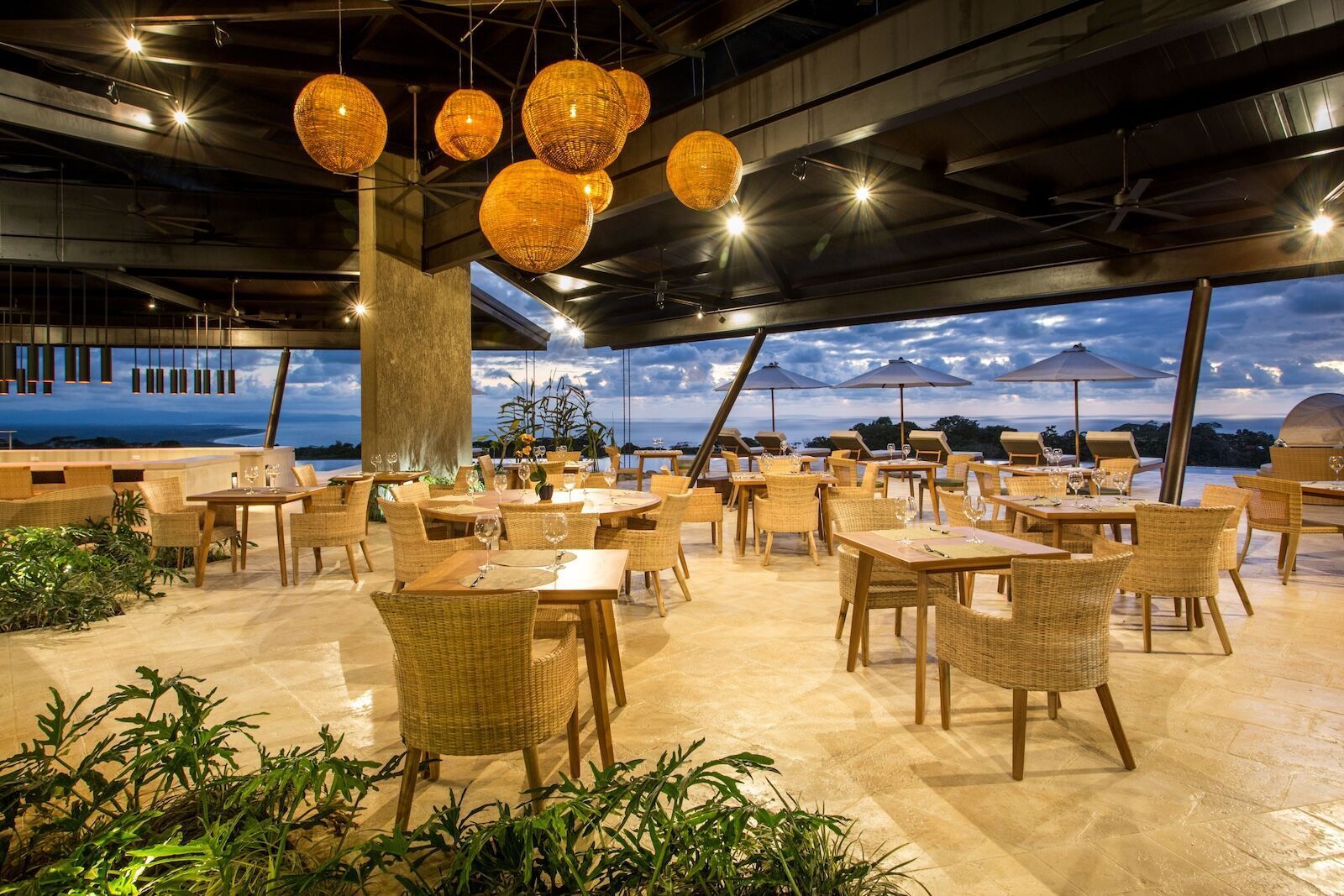 A restaurant with tables and chairs and a view of the ocean.