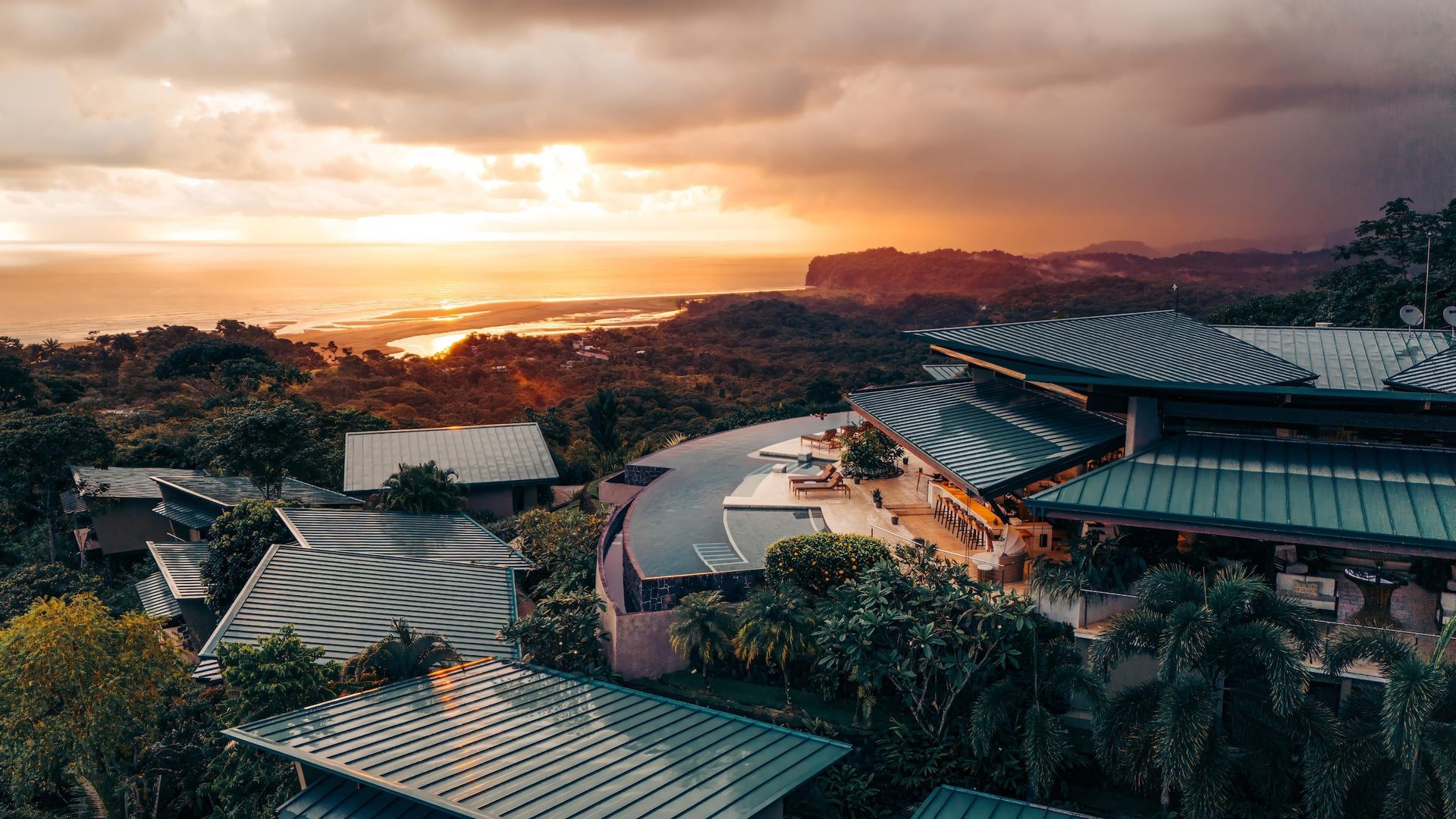 An aerial view of a large building surrounded by trees at sunset.