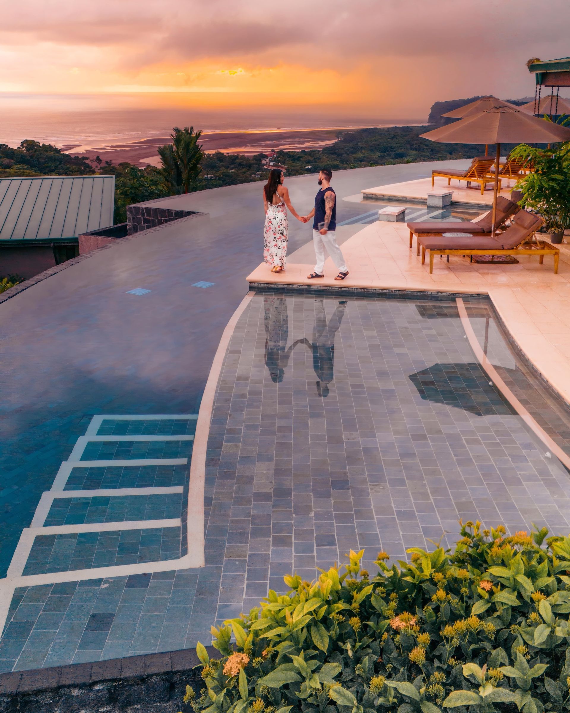 A man and a woman are standing next to a swimming pool.