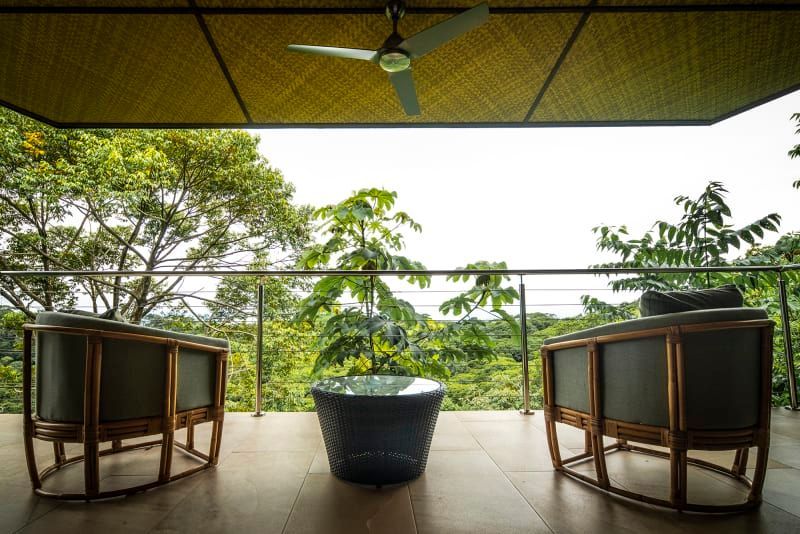 Two chairs and a table on a balcony with trees in the background