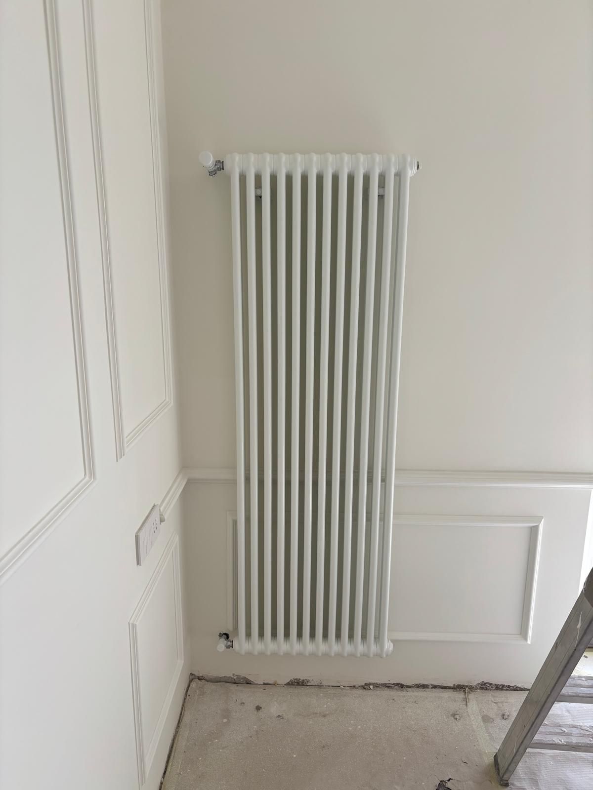 Tubi arancioni per il riscaldamento a pavimento installati a griglia su una base di plastica scura all'interno di una stanza in fase di ristrutturazione.