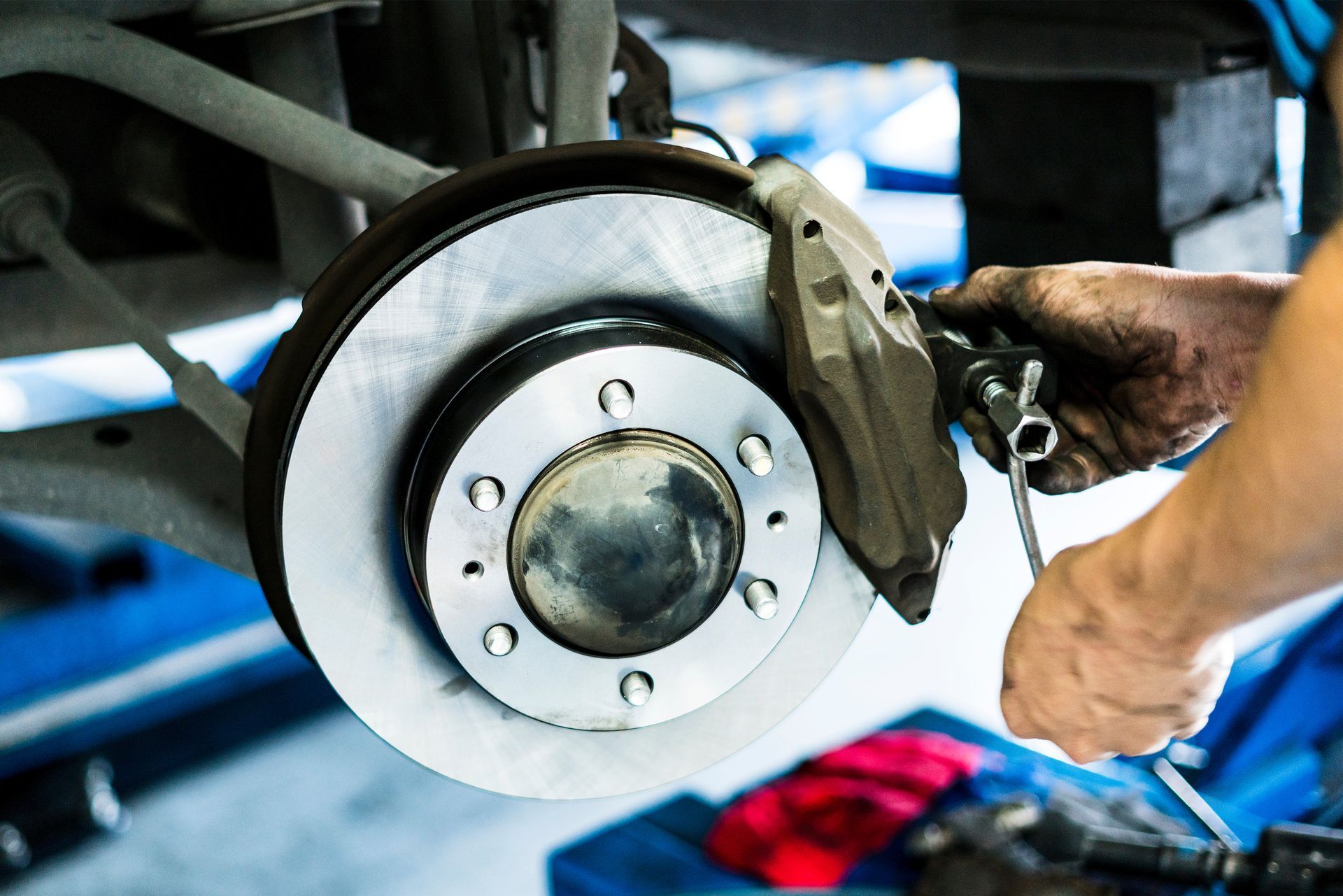 Close-up of a mechanic's hand performing brake repair services, assembling a car's disk brake
