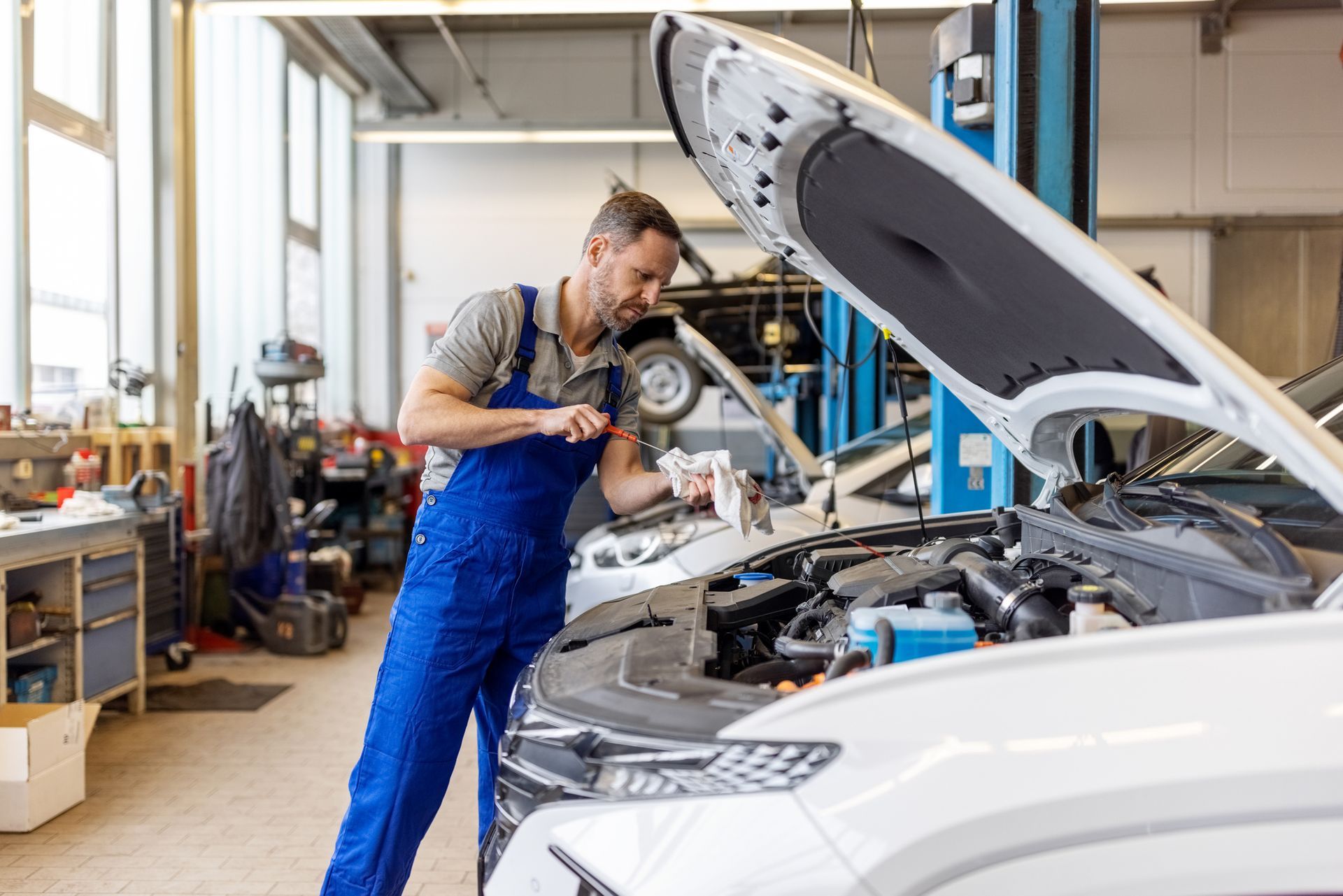 A professional mechanic checking the engine oil level of a car at a service station