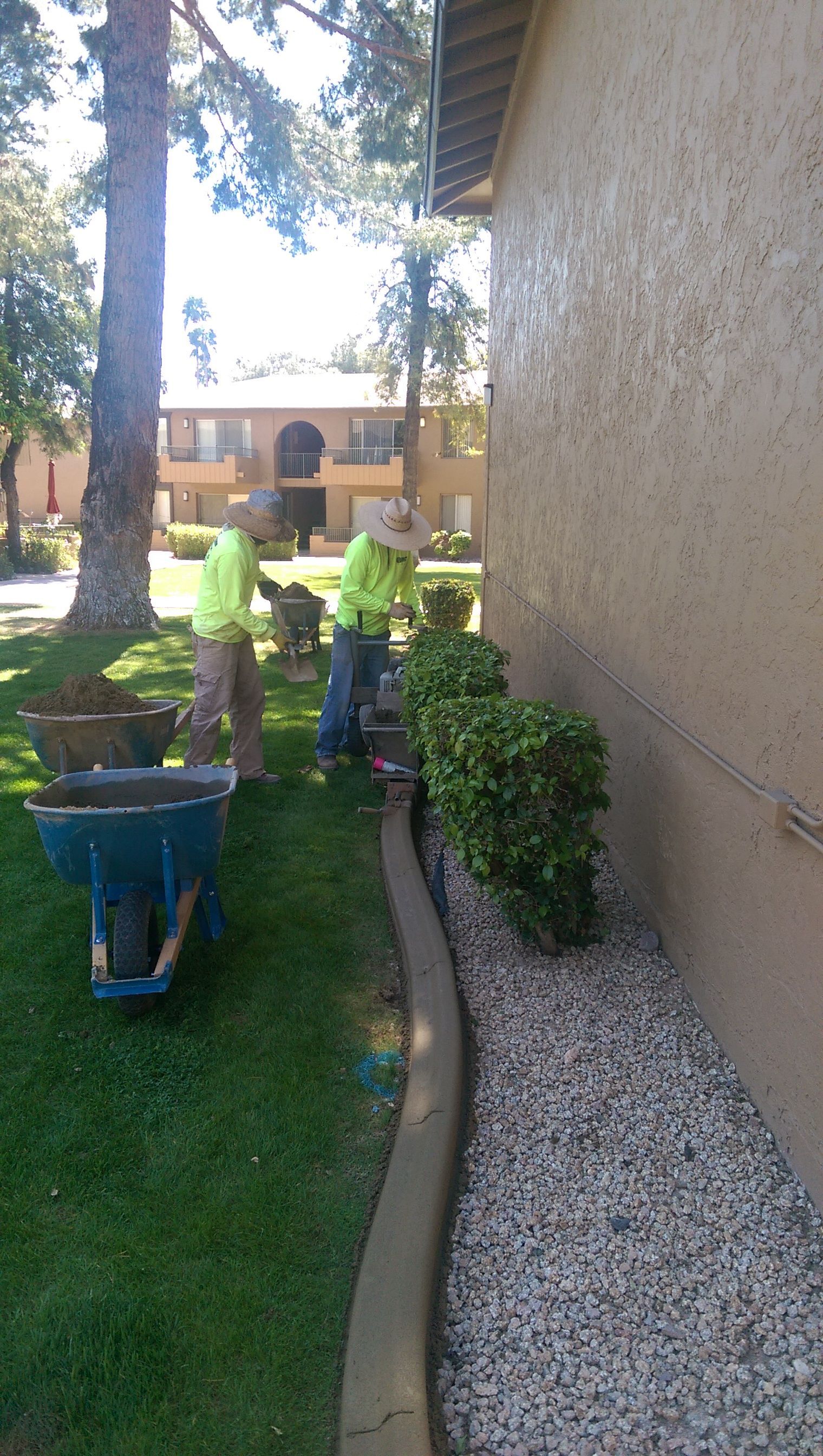 Two men are working in a yard next to a building.