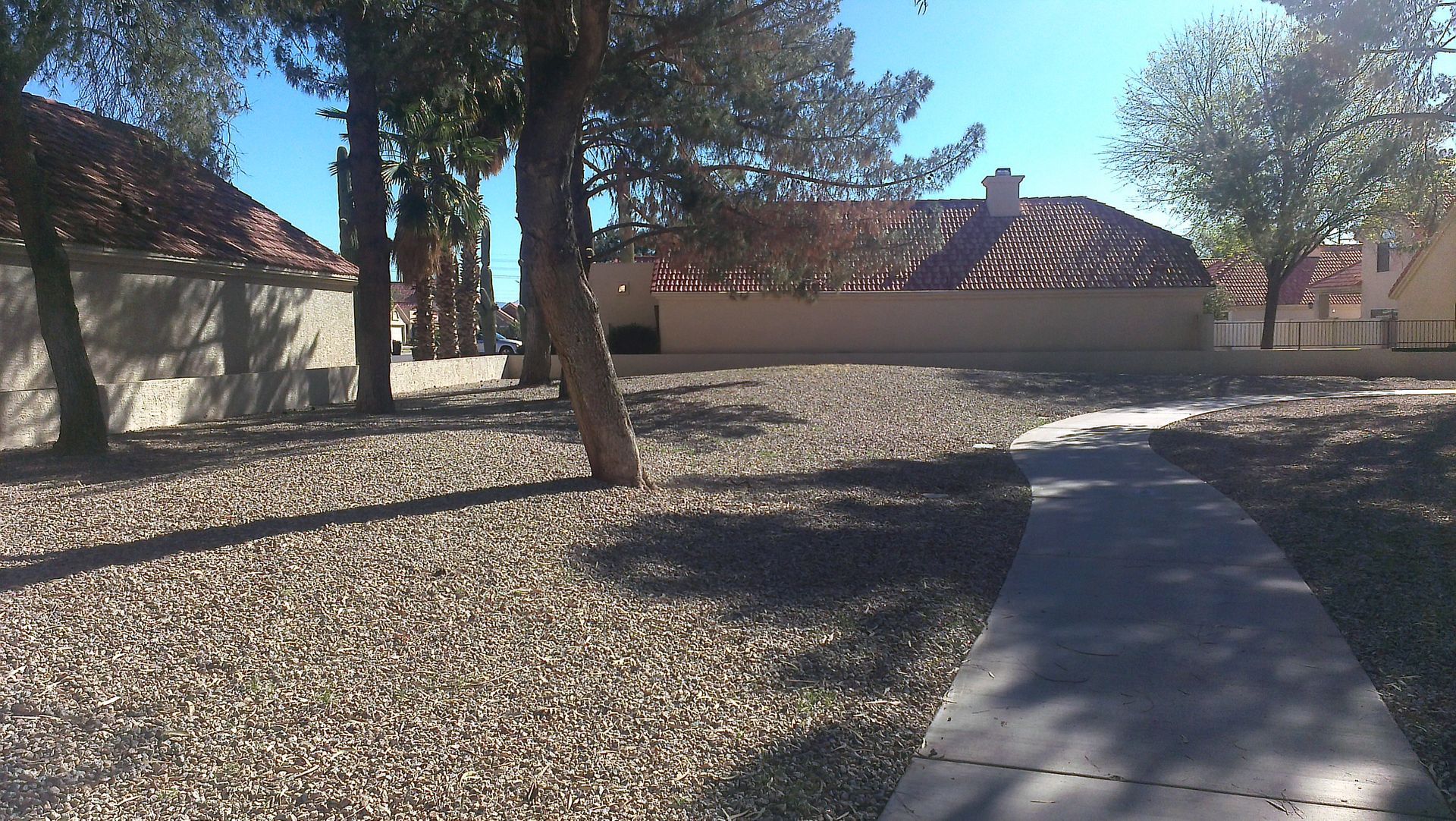 A concrete walkway leads to a house with a tiled roof