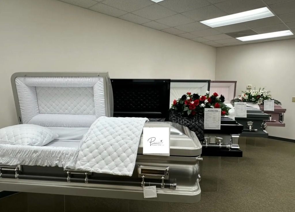 A man in a suit is sitting at a coffin at a funeral.