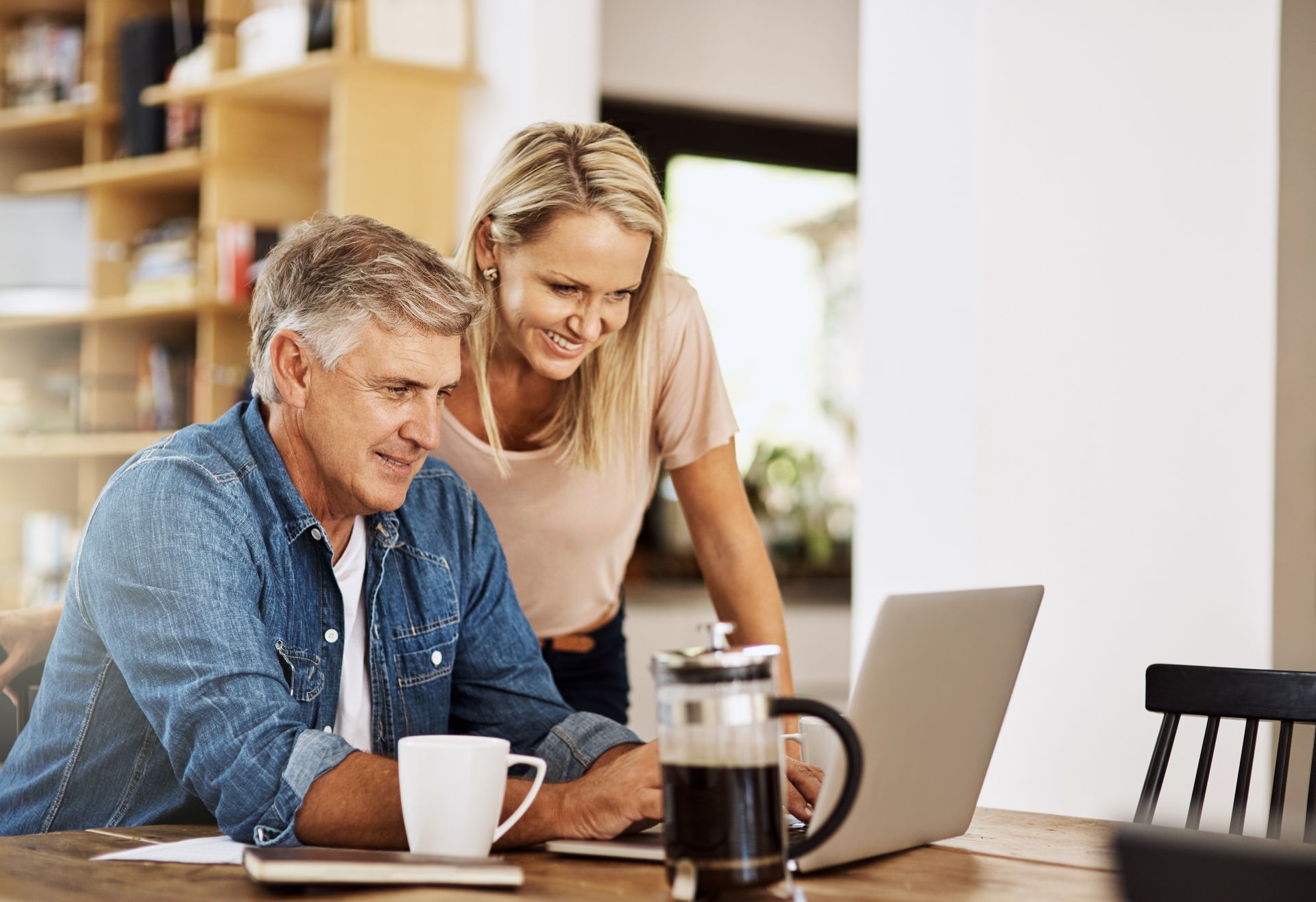 A man and a woman are sitting on a couch looking at a laptop computer.