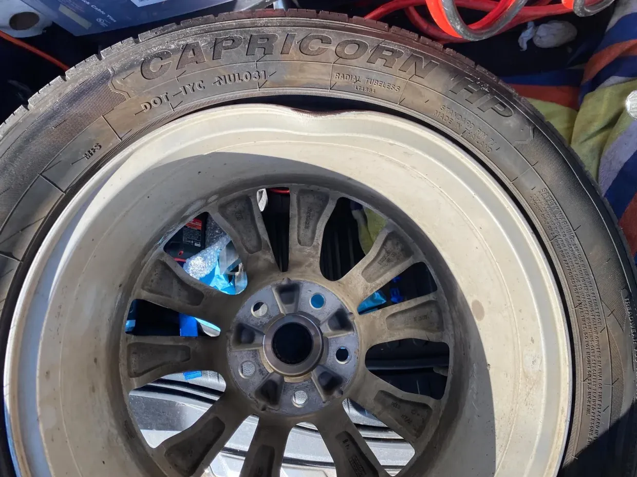 Damaged car tire on a rim, showing a bulge and potential rim damage.