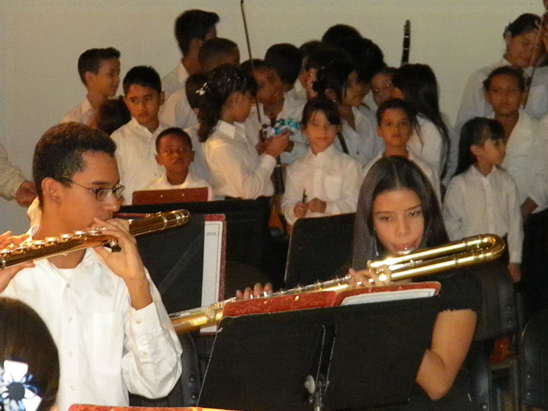 A man playing a flute and a woman playing a trombone in front of a crowd
