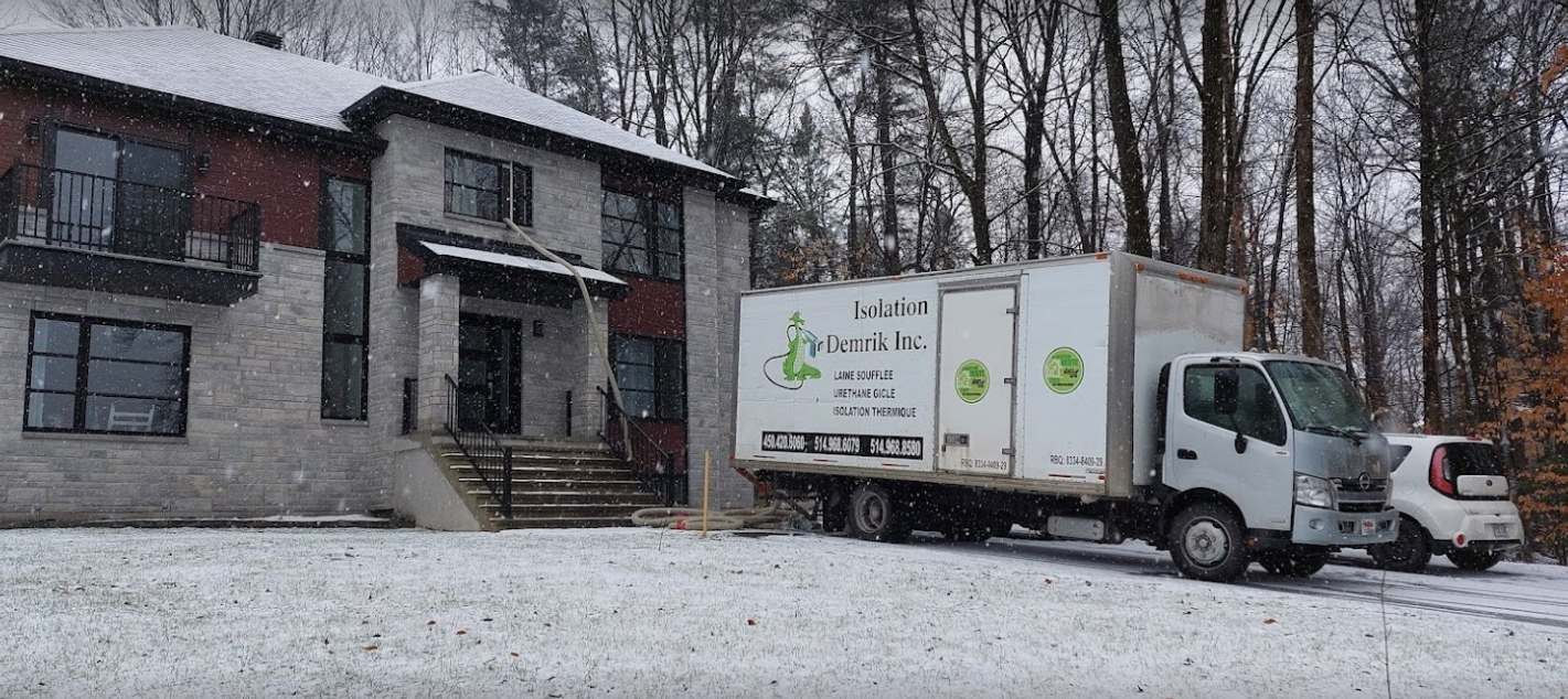 Un camion blanc est garé devant une maison sous la neige.