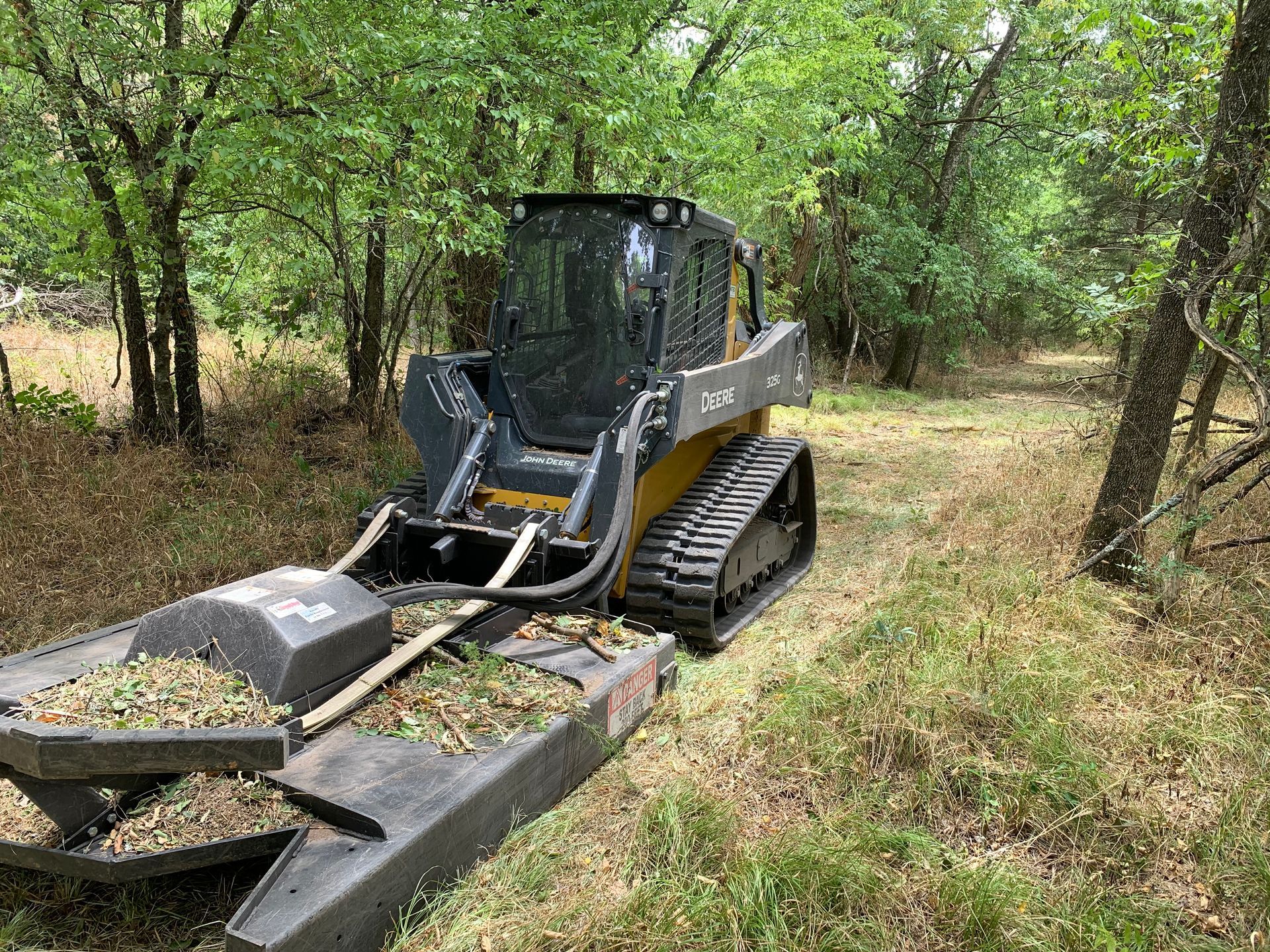 Skid steer brush cutting in woods.