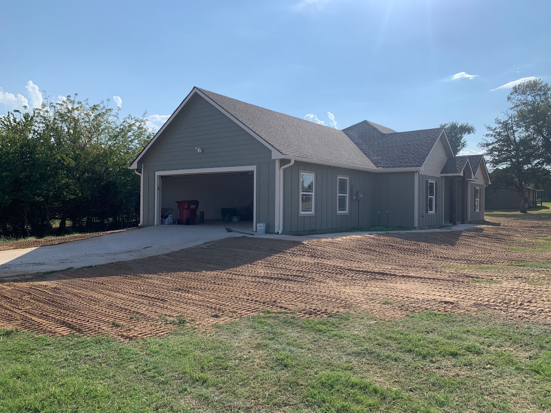 Gray house with attached garage, dirt lot smoothed out.
