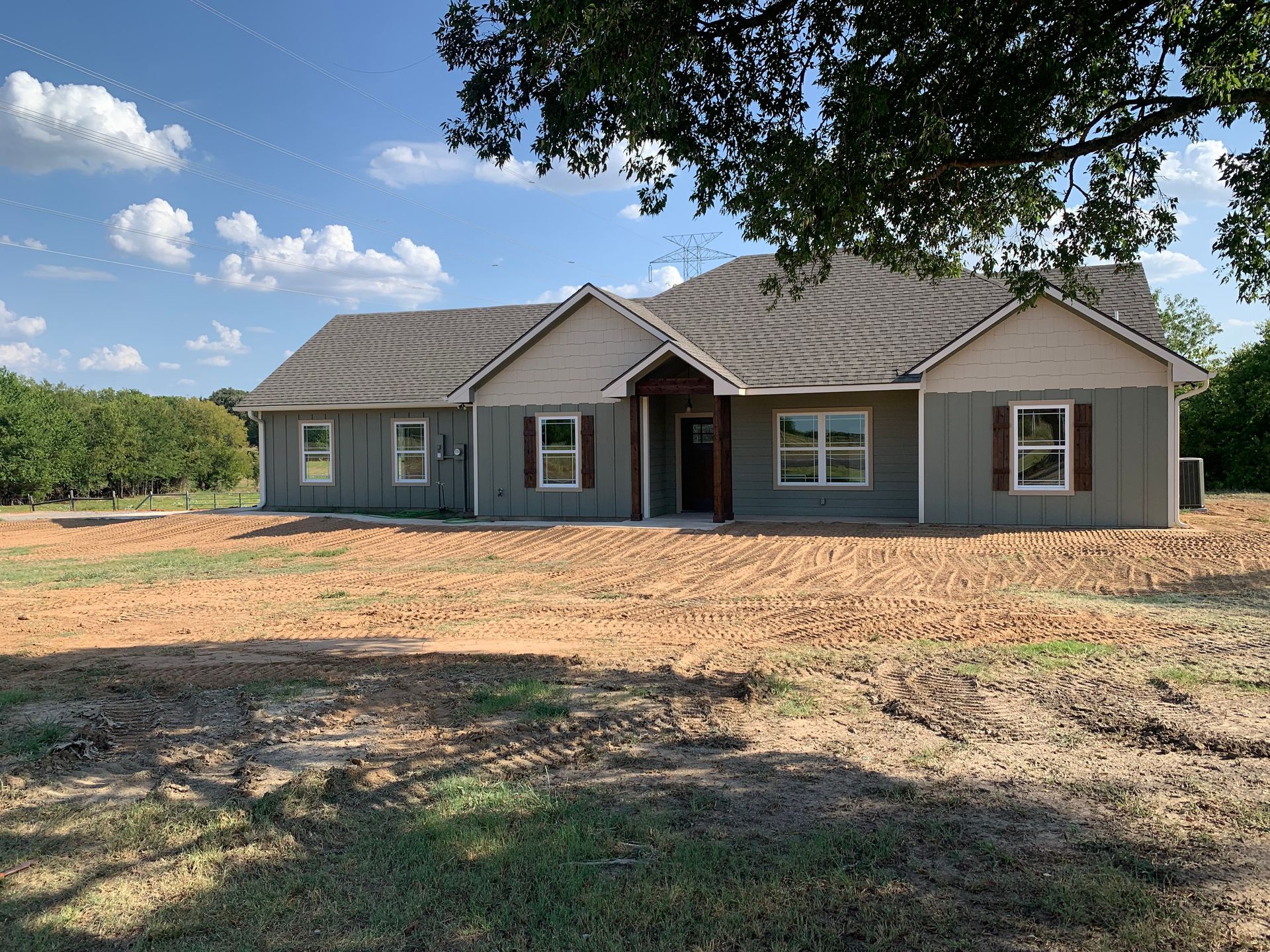 New gray house with brown shutters and trim, dirt yard clearing