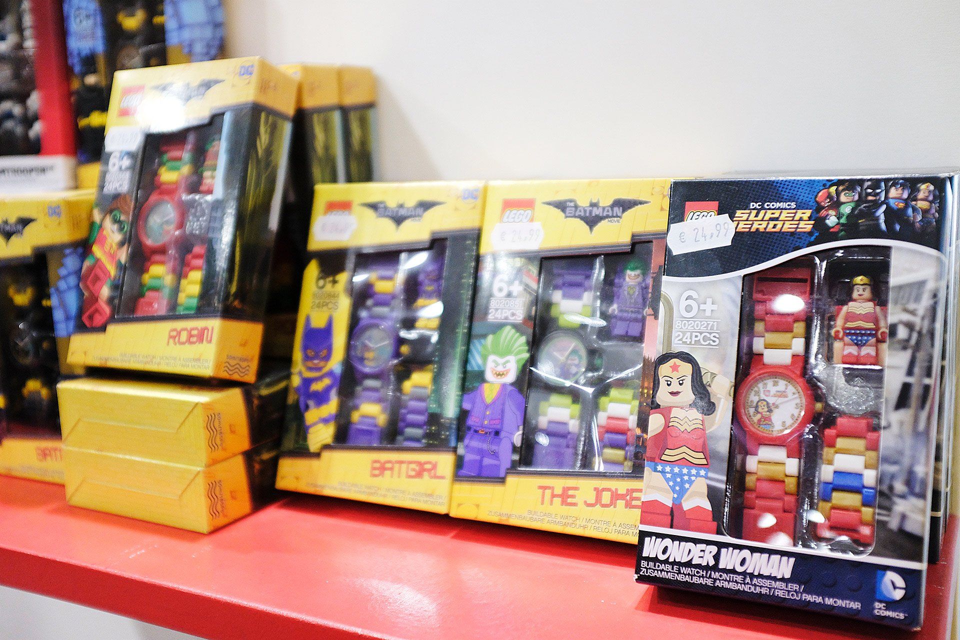 Un mucchio di orologi Lego sono appoggiati su un tavolo rosso.