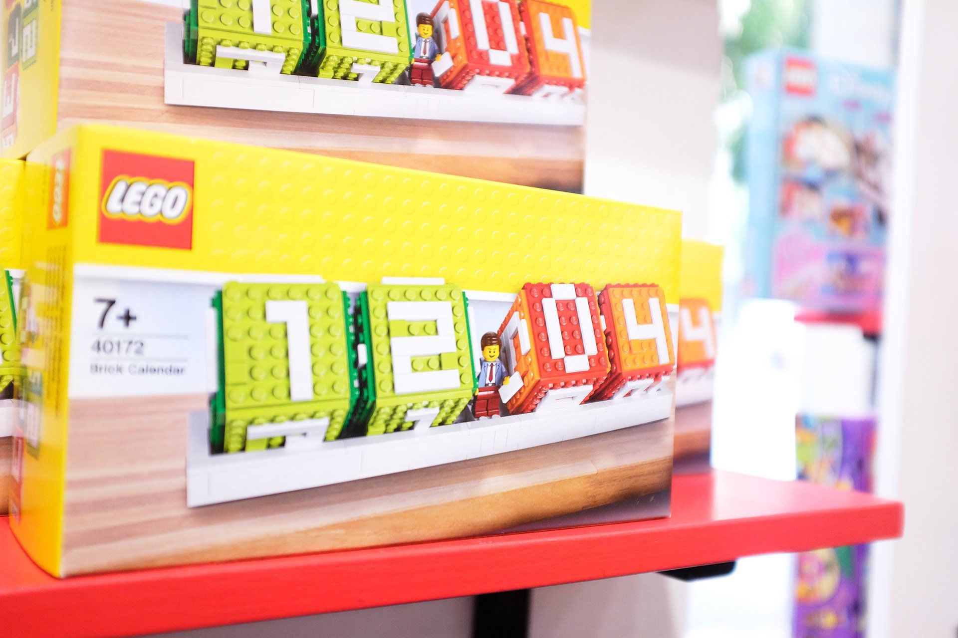 Una pila di scatole di Lego appoggiate su uno scaffale rosso.