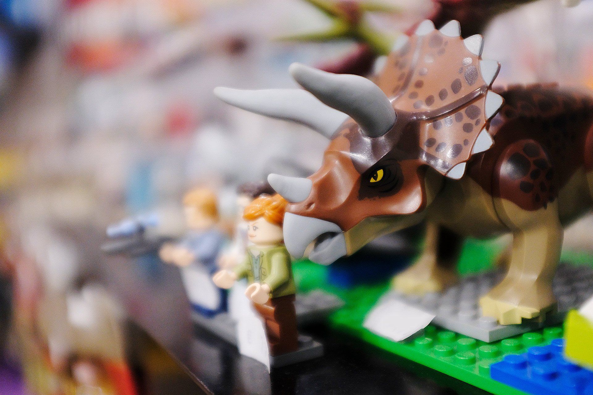 Un triceratopo giocattolo è appoggiato su un tavolo insieme ad altri dinosauri giocattolo.