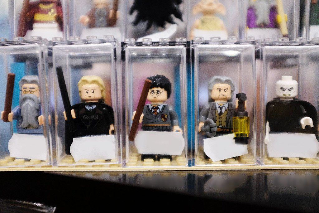 Un gruppo di personaggi Lego sono allineati in scatole di plastica trasparente.