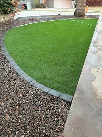 Green artificial turf bordered by dark pavers and gravel.