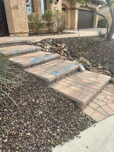 Stone steps leading up to a house, surrounded by gravel and landscaping. Blue markings on the steps.