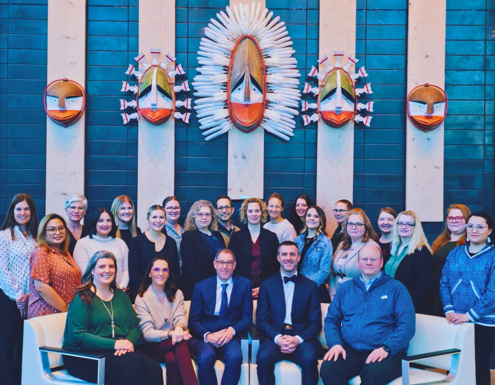 Group of people posing for a photo in front of a wall with abstract art.